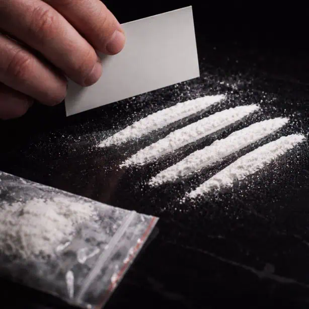 cocaine lines on table with hand preparing drug use